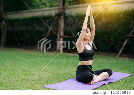 Radiate Vitality concept. A young asian female 30s jogger wearing sportswear stretching muscle in park and embraces the sun-kissed greenery, fusing exercise and nature to foster wellness and healing. Radiate Vitality concept. A young asian female 30s jogger wearing sportswear stretching muscle in park and embraces the sun-kissed greenery, fusing exercise and nature to foster wellness and healing. 111956918