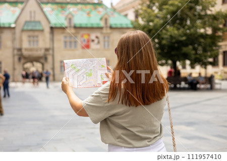 Happy tourist girl with map travels in Europe. Vacation concept by exploring interesting places to travel. Redhead Woman Searching locations at summer sunny day Happy tourist girl with map travels in Europe. Vacation concept by exploring interesting places to travel. Redhead Woman Searching locations at summer sunny day 111957410
