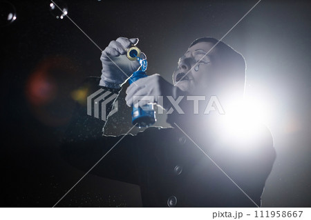 Minimal portrait of mime artist blowing soap bubbles on stage in spotlight, copy space 111958667