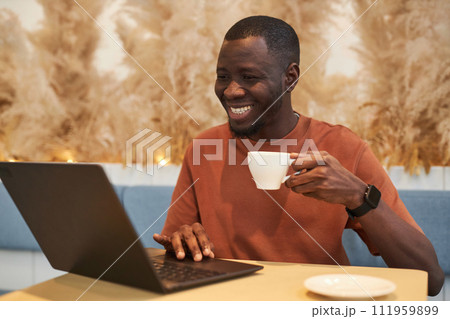 Portrait of smiling Black man in online meeting via laptop working in cozy coffee shop copy space Portrait of smiling Black man in online meeting via laptop working in cozy coffee shop copy space 111959899