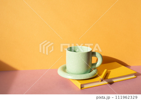 Notebook and colored pencil, coffee cup on pink desk. orange wall background. workspace 111962329