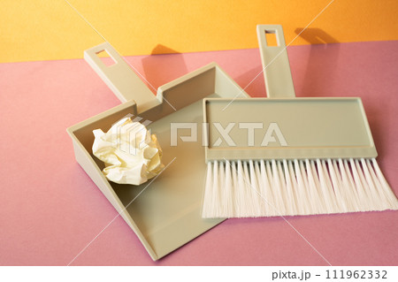 Gray plastic broom brush with dustpan on pink floor. orange wall background 111962332