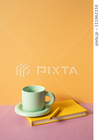 Notebook and colored pencil, coffee cup on pink desk. orange wall background. workspace 111962338