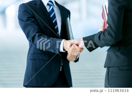 スーツを着た男女のビジネスマンが握手をする 111963818
