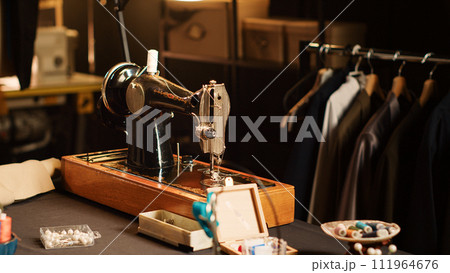 Fashion atelier sewing machine and tools on workshop table, luxury tailoring design and industrial materials. Workstation with fabric and pins for clothes manufacturing process. Close up. 111964676