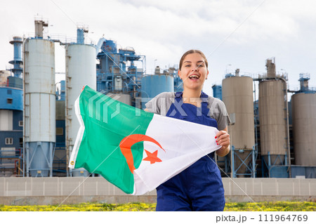 Cheerful young woman in uniform holds the national flag of Algeria 111964769