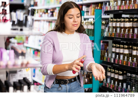 Girl with testers in perfumery, choosing perfume in cosmetic shop Girl with testers in perfumery, choosing perfume in cosmetic shop 111964789