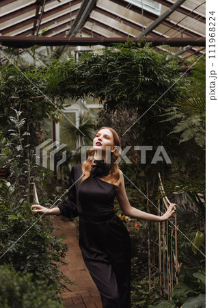 A woman walking through a greenhouse. 111968224
