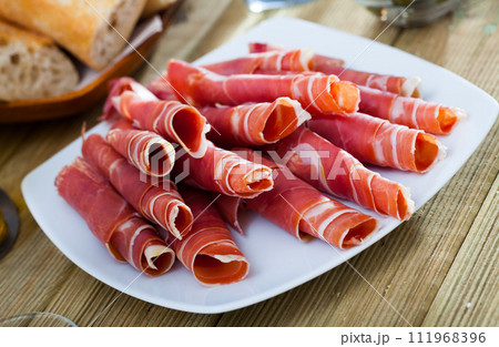 Traditional Spanish meal - rolls of iberian jamon served at plate 111968396
