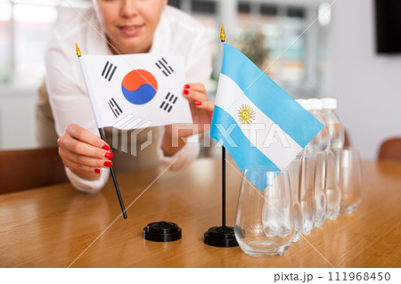 Preparing for business presentation - secretary places flags of Argentina and South Korea on negotiating table 111968450