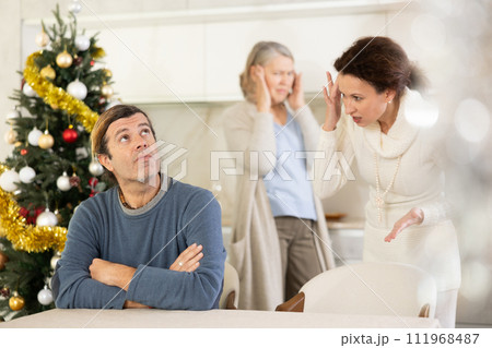 Elderly mother and woman during family quarrel accuse adult man on Christmas Eve 111968487