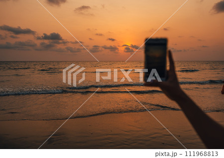 Sunset on the beach and mobile phone taking photos Sunset on the beach and mobile phone taking photos 111968813