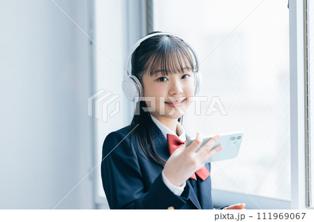 ヘッドフォンしてスマホを見ている女子中学生 111969067