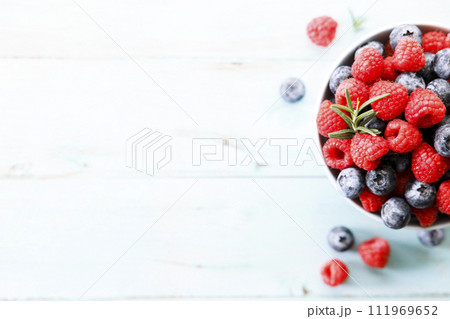 Ripe sweet blueberries and raspberries in a bowl. Closeup. 111969652