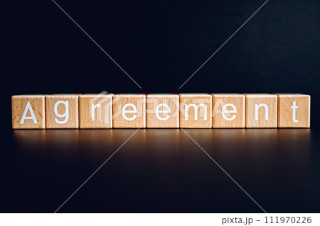 Wooden blocks form the text "Agreement" against a black background. Wooden blocks form the text "Agreement" against a black background. 111970226