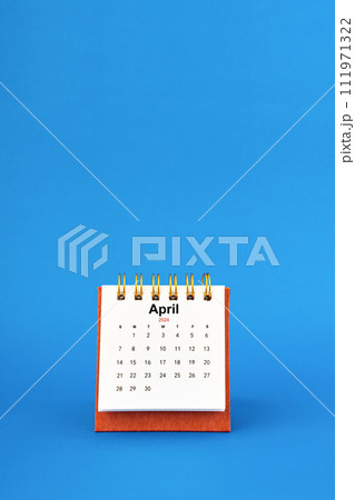 April 2024 white desk calendar on blue background. April 2024 white desk calendar on blue background. 111971322