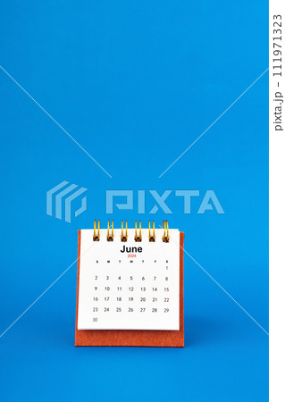 June 2024 white desk calendar on blue background. 111971323