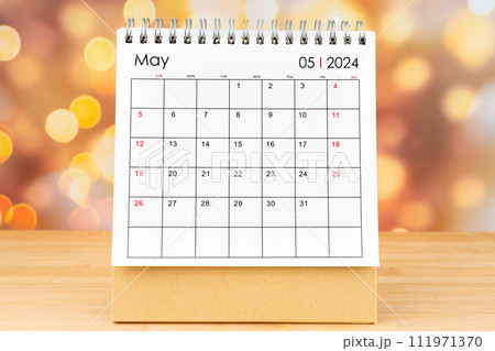 May 2024 desk calendar on wooden table with gold light bokeh background. May 2024 desk calendar on wooden table with gold light bokeh background. 111971370