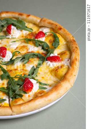 Freshly baked pizza with strawberries, cream cheese and arugula on a white plate. view from above 111971617
