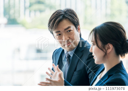 企業の会議室で会議・ミーティング・打ち合わせ・商談をする男女の会社員・ビジネスマン 111973078