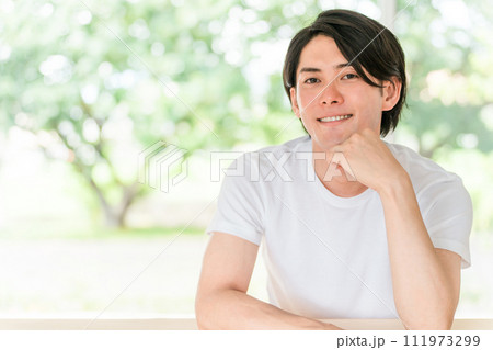 新緑の背景にいる白Tシャツ姿のさわやかな男性 新緑の背景にいる白Tシャツ姿のさわやかな男性 111973299