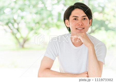 新緑の背景にいる白Tシャツ姿のさわやかな男性 新緑の背景にいる白Tシャツ姿のさわやかな男性 111973302