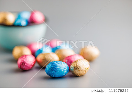 Easter chocolate eggs wrapped in aluminium foil on gray background. Easter chocolate eggs wrapped in aluminium foil on gray background. 111976235