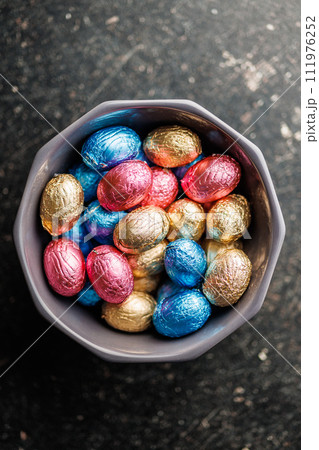 Easter chocolate eggs wrapped in aluminium foil in bowl. Top view. 111976252