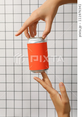 A metal can with a red wrapper in his hands 111976341