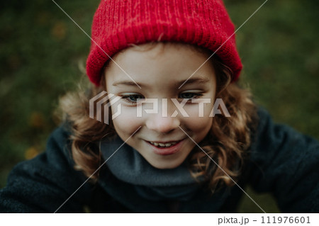 Portrait of little girl in red knitted hat. Red riding hood girl, little redcap lookalike. Portrait of little girl in red knitted hat. Red riding hood girl, little redcap lookalike. 111976601