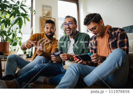 Best friends playing together on a gaming console, competing. Concept of male friendship, bromance. 111976656