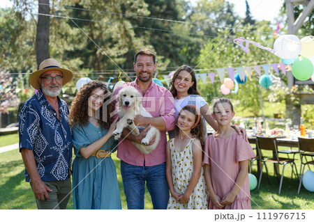 Family portrait at outdoor summer garden party. Family and friends standing, posing for a group photo. Multigenerational family. Family portrait at outdoor summer garden party. Family and friends standing, posing for a group photo. Multigenerational family. 111976715
