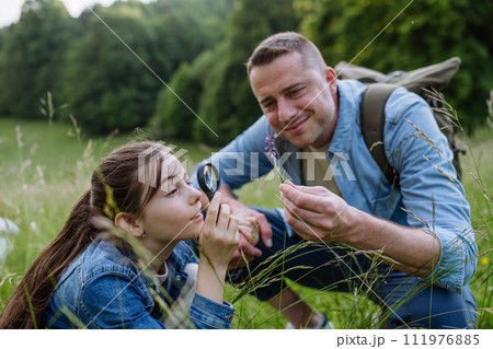 Dad with daughter, picking wildflowers in meadow, spending time together in nature. Concept of fathers's Day and fatherly love. Dad with daughter, picking wildflowers in meadow, spending time together in nature. Concept of fathers's Day and fatherly love. 111976885