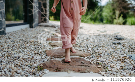 Close up of little girl walking barefoot near the forest cotage,weekend time during summer day. 111976920