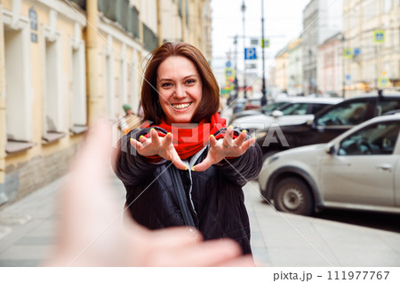 brunette female woman with bob hairstyle toothy smiling pulling hands in camera to another person's hand. European city street. follow me, date, love, valentine's day concept. lifestyle portrait brunette female woman with bob hairstyle toothy smiling pulling hands in camera to another person's hand. European city street. follow me, date, love, valentine's day concept. lifestyle portrait 111977767