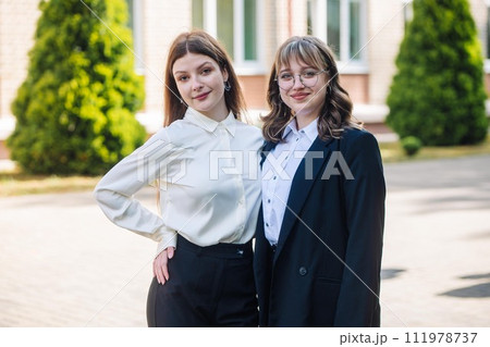 Portrait of two high school girls against the backdrop of the school. Portrait of two high school girls against the backdrop of the school. 111978737