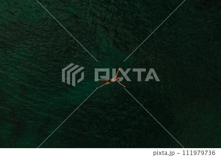 Aerial top nature view above green turquoise Adriatic sea in Albania. young woman swimming alone 111979736