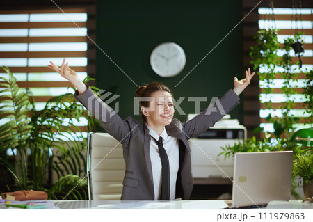 smiling female worker in green office throwing documents 111979863