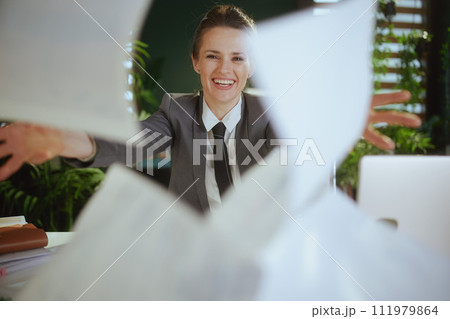 modern woman worker in modern green office throwing documents 111979864