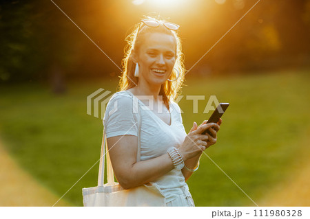 happy young 40 years old woman in white shirt using smartphone happy young 40 years old woman in white shirt using smartphone 111980328