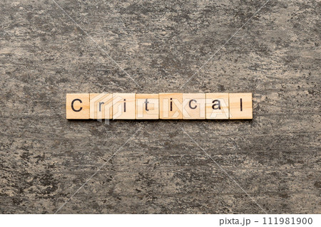 critical word written on wood block. critical text on table, concept critical word written on wood block. critical text on table, concept 111981900