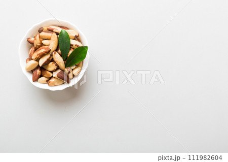 Fresh healthy Brazil nuts in bowl on colored table background. Top view Healthy eating bertholletia concept. Super foods Fresh healthy Brazil nuts in bowl on colored table background. Top view Healthy eating bertholletia concept. Super foods 111982604