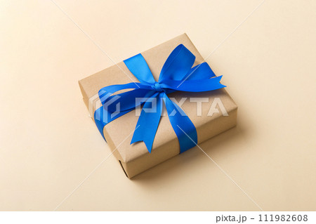 Wrapped christmas or other holiday handmade present in craft paper with colored ribbon. Present box, decoration of gift on table, top view with copy space 111982608