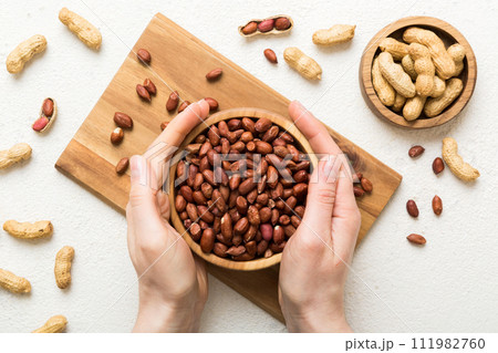 Woman hands holding a wooden bowl with peanuts. Healthy food and snack. Vegetarian snacks of different nuts 111982760