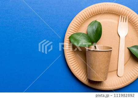 set of empty reusable disposable eco-friendly plates, cups, utensils on light white colored table background. top view. Biodegradable craft dishes. Recycling concept. Close-up 111982892