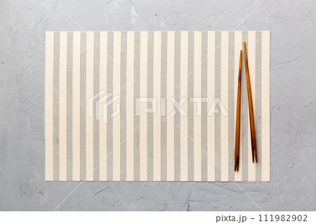 Two chopsticks and bamboo mat on cement background. Top view, copy space 111982902