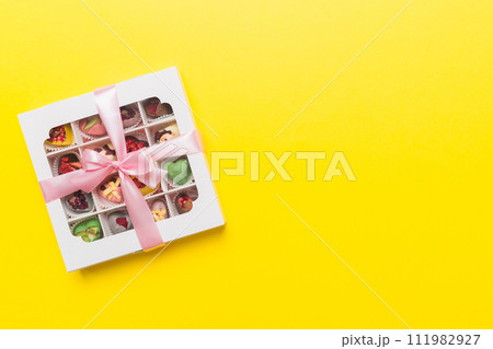 Box with sweet chocolate candies on color background, Various candy sweets. Valentines day gift box. Top view flat lay with copy space 111982927