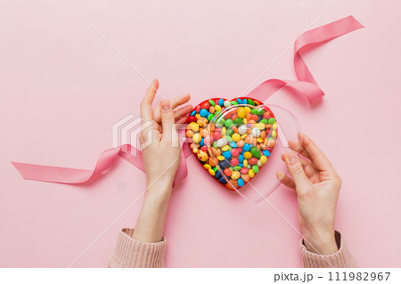 Female hands with delicious candies in box on color background 111982967