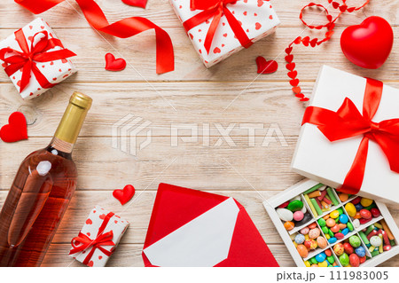 top view photo of st valentine day decor shopping, bag, wine, bottle, envelope, gift, box, candy and red heart on colored background with empty space. Frame background 111983005