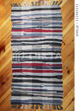 Rustic wicker rug on a wooden floor. Multi-colored Slavic carpet. 111983131